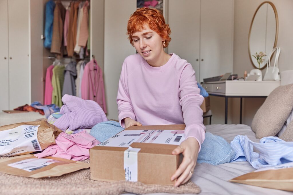 New distance selling concept. Young beautiful red haired woman sells clothes on secondhand clothing